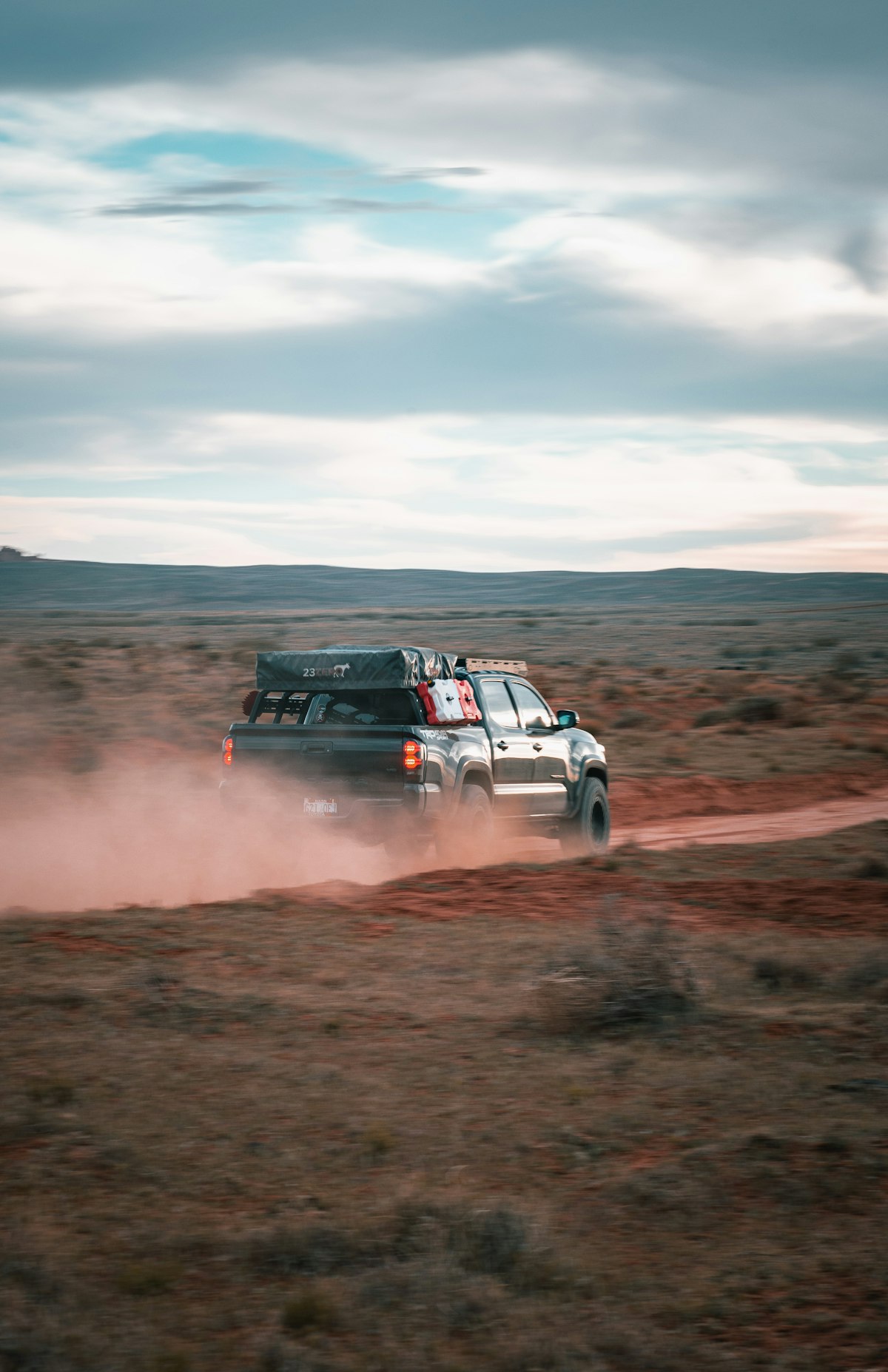 4x4 ute with rooftop tent on a red-dirt outback road