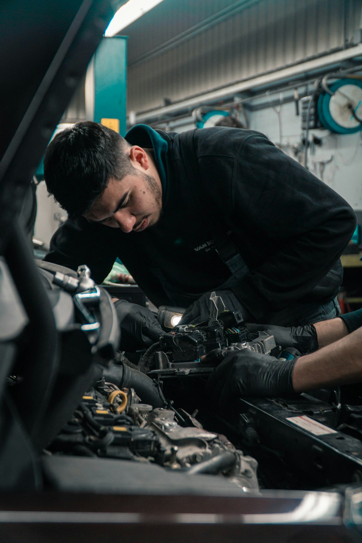 Mechanic working on a car engine with diagnostic light